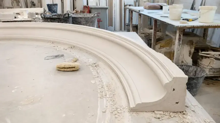 Pieza curva de escayola sobre la mesa del taller